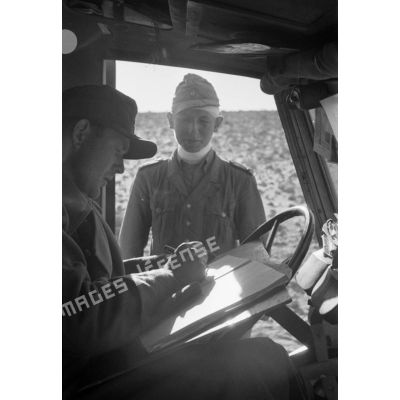 Un Oberleutnant des Sanitätstruppen établit un document dans la cabine d'un véhicule.