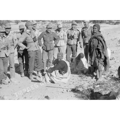Un groupe de soldats entoure deux hommes et un jeune garçon.
