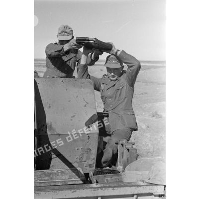 Deux servants rangent des chargeurs d'obus de 2 cm FlaK 38 installé sur un camion Ford.