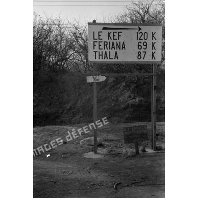 Des panneaux  indiquent les distances vers les ville de Feriana, La Kef, Thala tandis qu'un panneau allemand indique l'axe de progression de la 10-Pz.Div.
