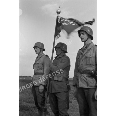 Le porte-fanion d'une des unités de volontaires arabes est entouré par deux sous-officiers allemands.