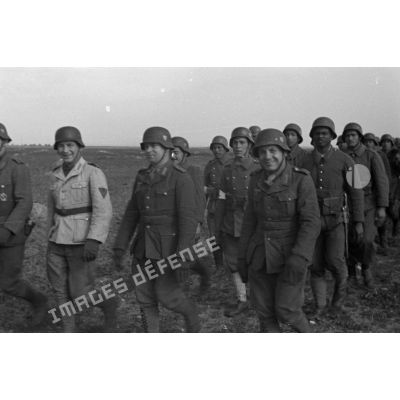 Une colonne de volontaires qui marchent au pas, le premier rang est occupé par des cadres allemands.