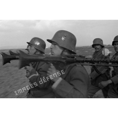 Gros-plan sur des volontaires défilant avec des mitrailleuses MG-34 sur l'épaule.