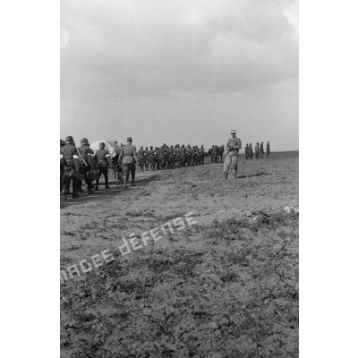 Les volontaires défilent en colonne devant un officier allemand.