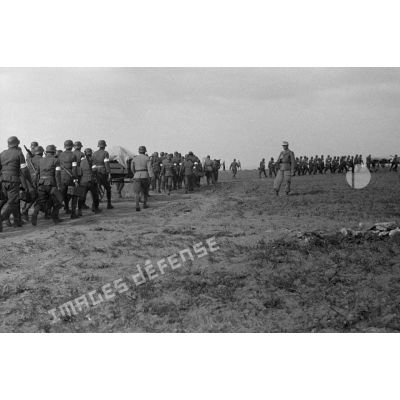Les volontaires défilent en colonne devant un officier allemand.