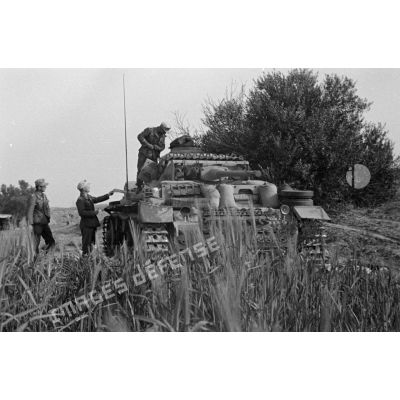 Un char Panzer III (Pz-III Ausf-L) dont l'équipage a en partie débarqué, est posté sous un arbre.