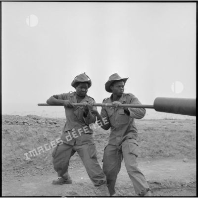 Nettoyage du fût d'un canon de 105 mm par des soldats du 5e bataillon du 10e régiment d'artillerie coloniale (RAC) après un tir à Montagnac.