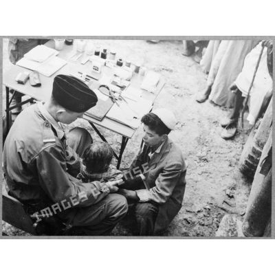 Le médecin militaire soigne un enfant algérien au poste du 72e groupe d'artillerie (GA) à Zemmoura.