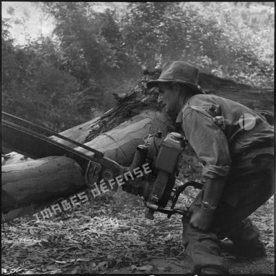 Sergent du 37e bataillon du génie tronçonnant un arbre pour la construction d'une route en Kabylie lors de l'opération Basque.