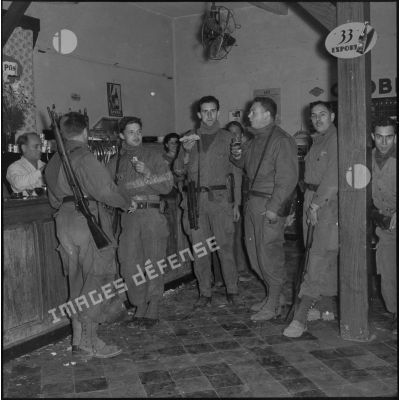 Moment de détente dans un café bar pour des rappelés du Service cinématographique des Armées (SCA) après une patrouille de nuit à Alger.