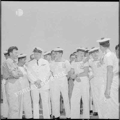 Un reporter militaire et un officier entourés de matelots du navire-école Jean Bart.