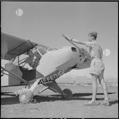 Vérification d'un avion Piper L 18 C avant son départ en mission.