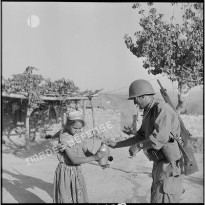 Une petite fille offrant à boire à un fusilier-marin du 2e bataillon de la 1re demi-brigade de fusiliers-marins (DBFM).