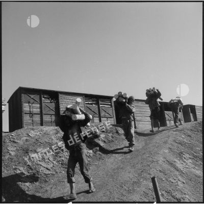 Des mineurs déchargent des rondins de bois du train, à la mine de Colomb Béchar.