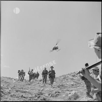 Un hélicoptère Bell 47 G survole des chasseurs alpins pendant leur progression.