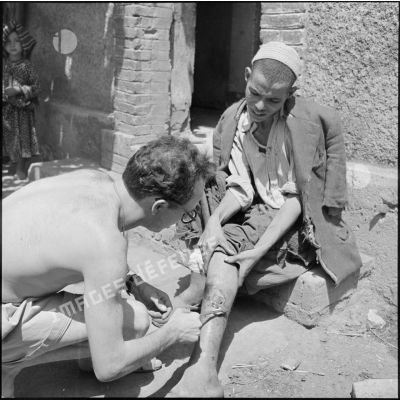 Le sergent Maurice Lebon de la 2e compagnie du 2e régiment d'infanterie coloniale (RIC) soignant un homme blessé à la jambe dans la région des monts du Sidi Ali Bou Nab.