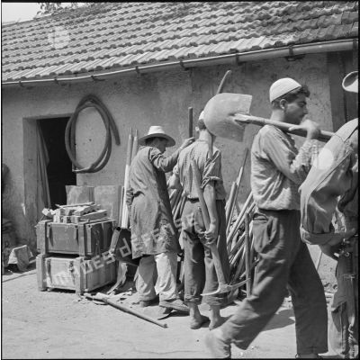Des soldats de la 2e compagnie du 2e RIC et des ouvriers s'équipant d'outils.