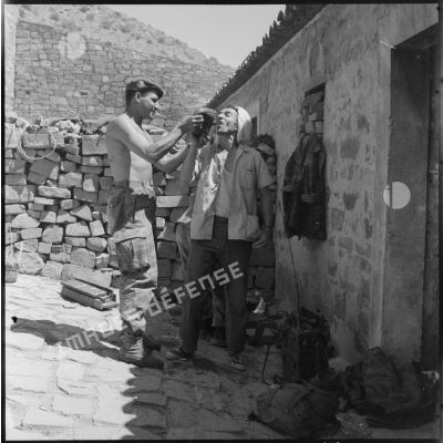 Un soldat du 3e régiment étranger de parachutistes (REP) apprenant à un habitant de la région de Bordj Bou Arreridj à boire à la gourde basque.