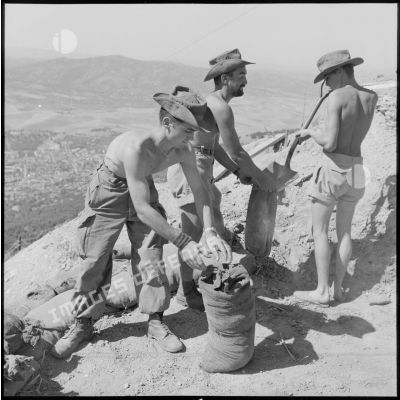 Des soldats de la 1re compagnie du 45e BIC remplissant des sacs de terre.