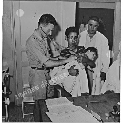 Un médecin militaire examinant un enfant algérien à Aïn Abid.