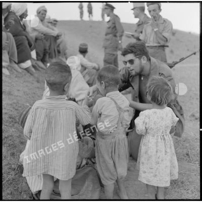 L'infirmier du 1er bataillon de la 1re demi-brigade de fusiliers-marins (DBFM) distribuant des bonbons aux enfants de Beni Menir.