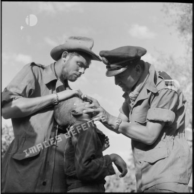 Le docteur Lamblain et l'infirmier Paul Druon du 1er bataillon de la 1re demi-brigade de fusiliers-marins (DBFM) soignant un enfant.
