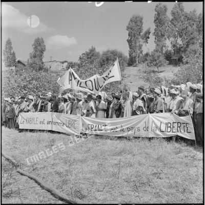 Portant des calicots couverts d'inscriptions patriotiques, les habitants du douar Mechtrass, rassemblés, attendent la revue du général Olié.