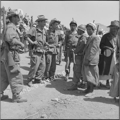 Un groupe de spahis discute avec deux supplétifs algériens (en uniforme) et un membre du groupe d'autodéfense.