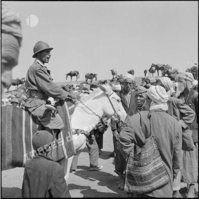 Un membre de la harka, à cheval, entouré par des fellahs.