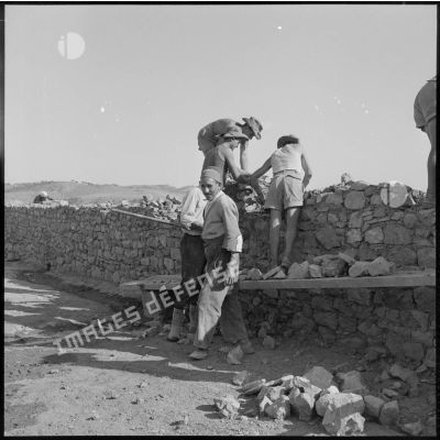 Trois soldats du 50e BG travaillent à la réfection d'un mur d'enceinte du fortin Caravansérail, construit en 1873 peu après la révolte kabyle.