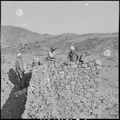Deux soldats du 50e BG travaillent à la réfection d'un mur d'enceinte du fortin Caravansérail avec des Algériens.