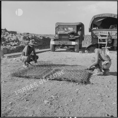 Deux soldats du 50e BG travaillent à la construction d'un toit en genêt pour le foyer.