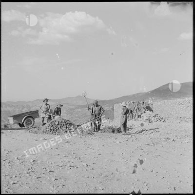 Deux soldats du 50e BG travaillent à la réfection d'un mur d'enceinte du fortin Caravansérail avec des Algériens.