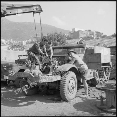 Trois soldats de la 69e CRD démontent ou remettent en place le moteur d'un Half-track.