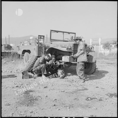 Trois soldats de la 69e CRD travaillent sur la barre de direction d'un camion.