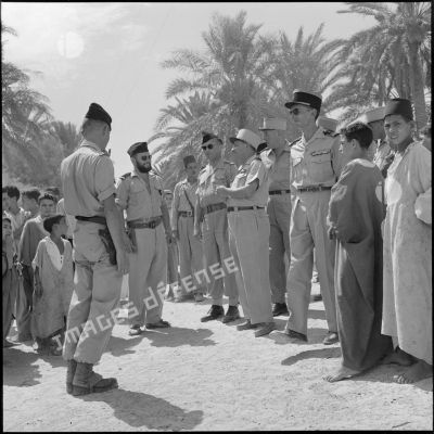 Au cours de sa visite de l'oasis de M'Doukal le général Vanuxen discute avec les officiers qui l'entourent.<br>