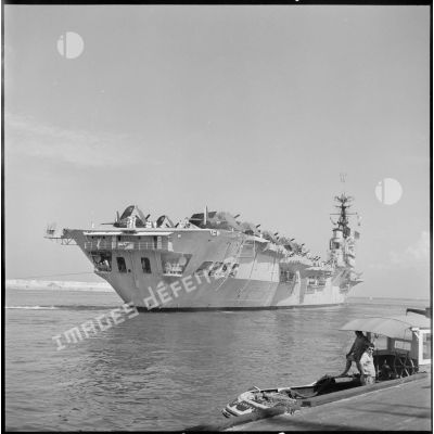 Le porte-avions Arromanches est remorqué dans le port d'Alger.