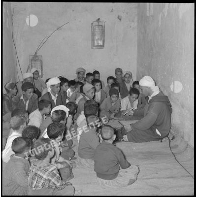 Un homme s'occupe des enfants rassemblés dans une petite salle.