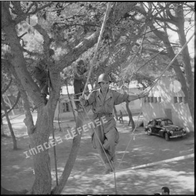 Au camp du Lido à Hussein Dey, un appelé effectue un parcours d'entraînement dans les arbres.