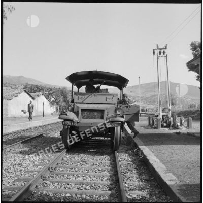Un véhicule blindé stationne sur des rails de chemin de fer.
