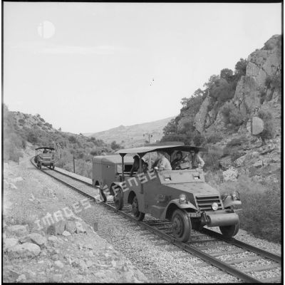 Deux véhicules blindés patrouillent sur des rails de chemin de fer.