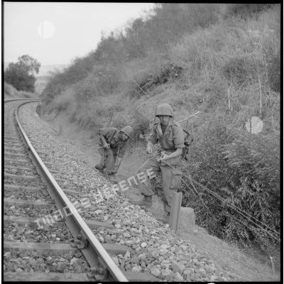 Deux soldats sécurisent les abords des voies de chemin de fer.