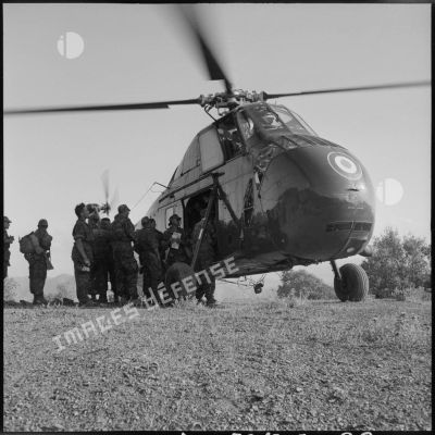 Un groupe de soldats du 2e régiment de parachutistes coloniaux (RPC) est regroupé devant un hélicoptère en marche.