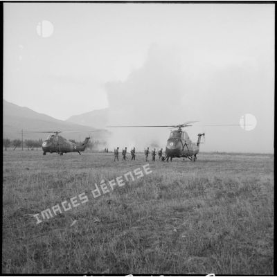 Les soldats du 2e régiment de parachutistes coloniaux (RPC) embarquent à bord d'un hélicoptère sur un terrain vague.