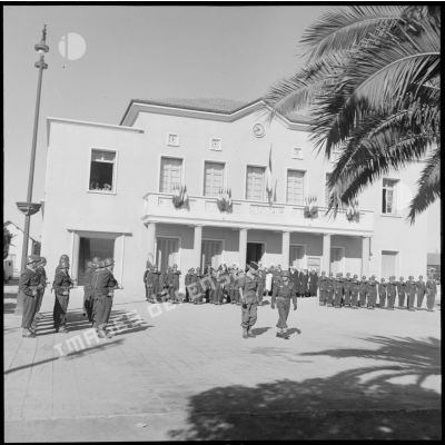 Un groupe de soldats présente les armes devant la mairie d'Aïn Temouchent.