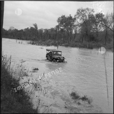 Des soldats en jeep remontent une route inondée près de Bône, le jour de la visite du secrétaire d'état Max Lejeune et du général Salan.