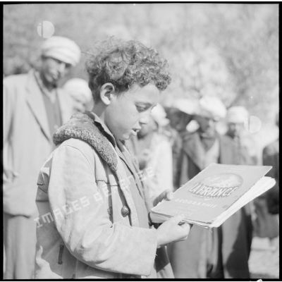 Un écolier du village de Gallieni pose avec son livre "La France et l'Union française" distribué par la compagnie de haut-parleur et de tracts.