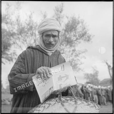Un habitant de Gallieni en tenue traditionnelle pose avec un tract distribué par la compagnie de hauts-parleurs et de tracts (CHPT).