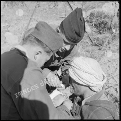 Deux soldats soignent un blessé algérien lors d'une séance d'action psychologique organisée près d'un poste de contrôle militaire.