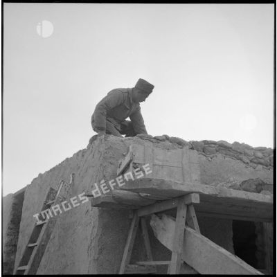 Un soldat sur le toit d'une mechta en chantier en Algérie.